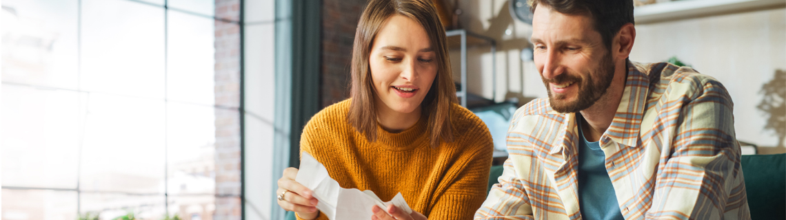 Молодая пара рассматривает бумагу с финансовыми данными